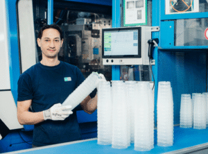 Dipendente durante la produzione di bicchieri riutilizzabili con una macchina per stampaggio a iniezione